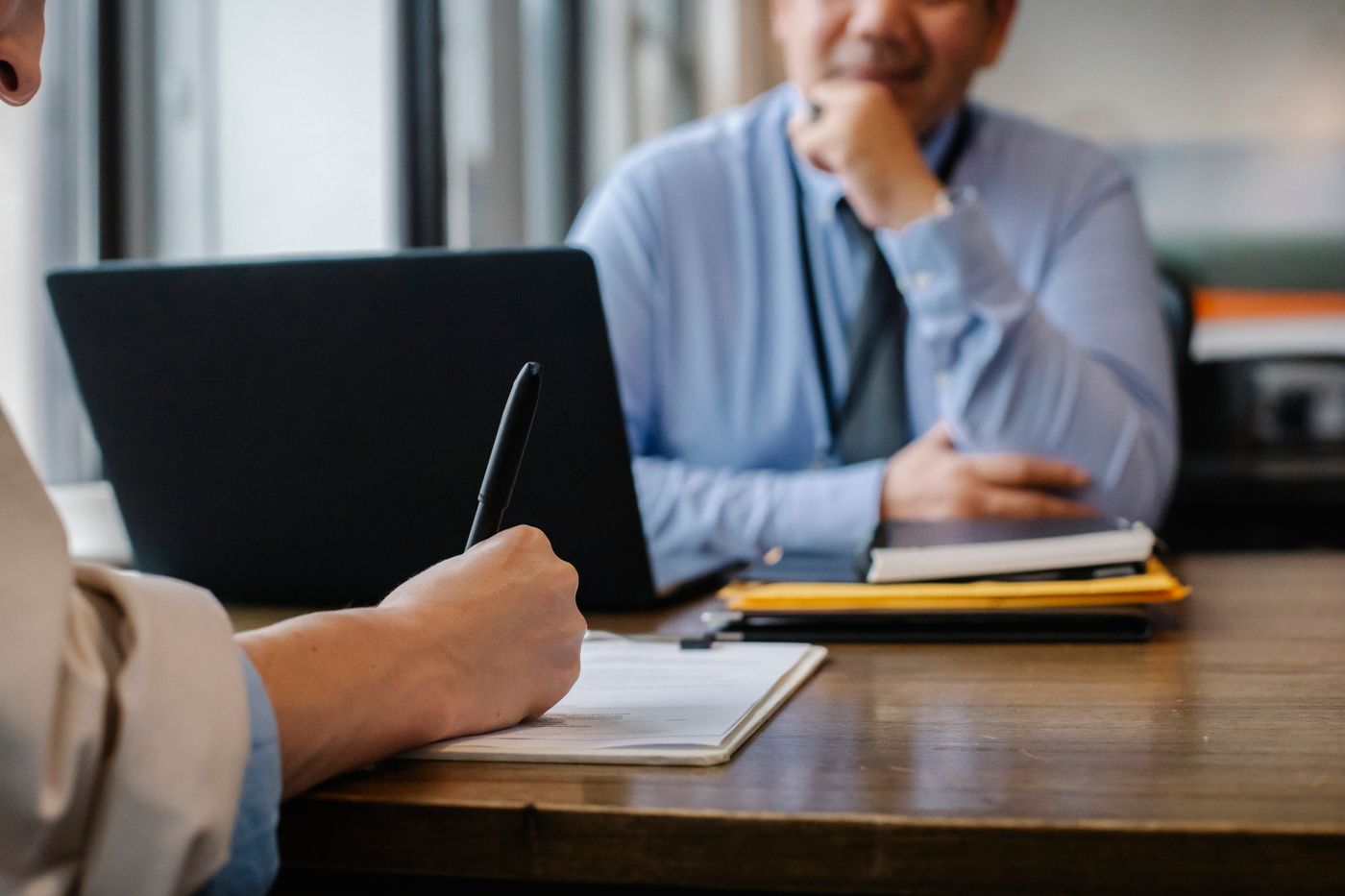 Abogada tomando notas durante una reunión con un cliente en el despacho
